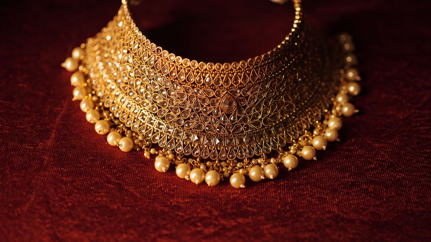 Gold-tone polki choker with pearl drops on red velvet